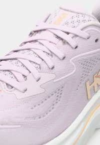 Chaussure de sport violet clair avec une tige en maille, des lacets plats et des accents texturés. Dotée d'une semelle rembourrée pour le confort et le soutien.