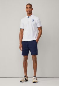 Λευκό πόλο μπλουζάκι με μπλε λεπτομέρειες και κεντητ�ό "3" σε συνδυασμό με ναυτικές βερμούδες. Τα παπούτσια συνδυάζουν μπεζ, ναυτικό και μαύρο χρώμα.