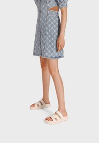 Sandali con plateau rosa pallido con due fasce larghe, realizzati in materiale liscio. Abbinati a un vestito azzurro chiaro con motivo e maniche a sbuffo.