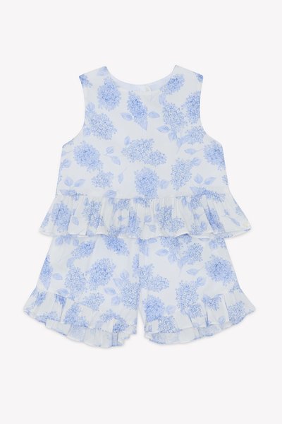 Blomstertrykt to-delt antrekk i lyseblått og hvitt, med volanger og shorts, laget av lett stoff med en jevn tekstur.