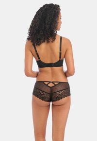 Zwart bh en kantschort set. Bh heeft verstelbare banden en haaksluiting. Shorts hebben een doorschijnend gaaspaneel en gegolfde kantdetail.