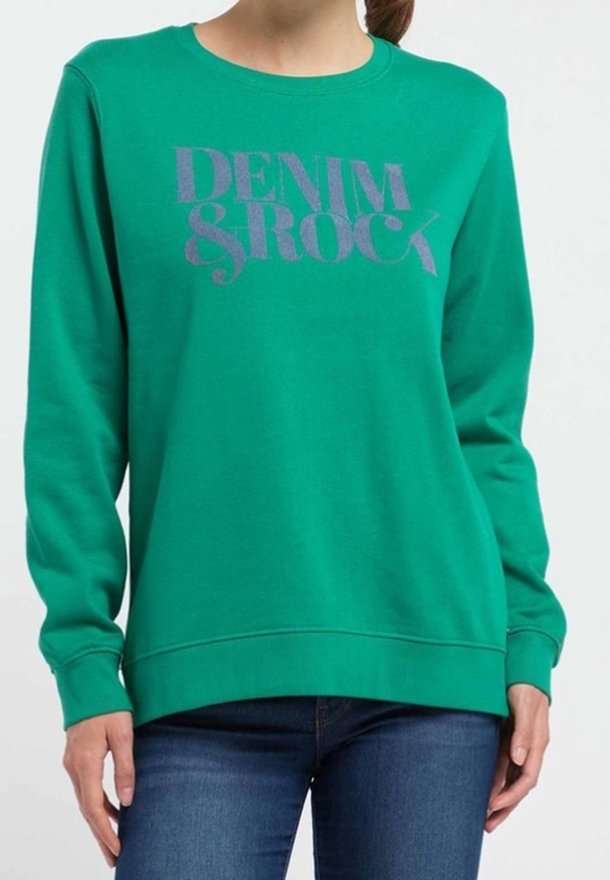 Sudadera verde hecha de material suave con un gran texto morado que dice "DENIM & ROCK." Diseño clásico de cuello redondo con puños y dobladillo acanalados.
