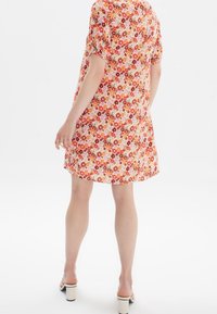 Robe à imprimé floral en tissu léger, avec des manches courtes à volants, une coupe décontractée et un motif multicolore de petites fleurs.