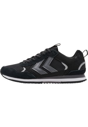 Zwarte sportschoenen van een mix van suède en mesh, met grijze accenten en drie diagonale strepen. Eenvoudige witte zool en gestructureerde bovenkant.