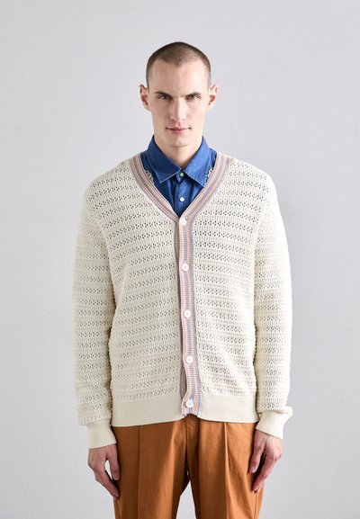 Cardigan a maglia colore crema con scollatura a V, caratterizzato da una trama a rete aperta e bordo a strisce blu e arancione in contrasto, chiuso con bottoni bianchi.