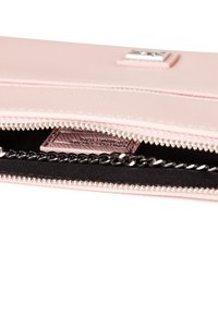 Portafoglio in pelle rosa con cerniera argentata, interno nero, dettaglio a catena e piccola etichetta del marchio all'interno.