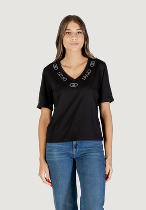 T-shirt nera a maniche corte con scollo a V, caratterizzata da un design del logo decorativo e adornata con cristalli intorno all'area del colletto.
