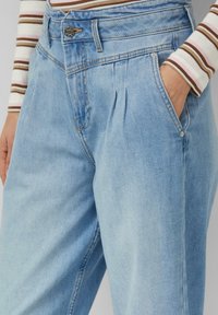 Jasnoniebieskie dżinsowe spodnie z wysokim stanem, plisowanym przodem, bocznymi kieszeniami i srebrnym zapięciem na guzik. Gładka faktura i casualowy design.