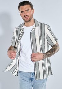 Kurzärmeliges, knöpfbares Hemd aus schwarz-weiß gestreiftem Stoff mit strukturiertem Gewebe. Verfügt über eine Brusttasche und einen regulären Schnitt.