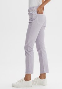 Jean en denim lilas avec une coupe slim droite, cinq poches et ourlets retroussés, associé à des baskets blanches. Le tissu semble doux avec une texture subtile.