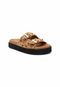 Sandal de deslizamiento marrón con tachuelas doradas, dos hebillas ajustables y una suela de goma negra. Textura suave con un diseño plano y ancho.