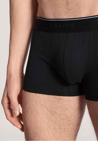 Zwarte katoenen boxershorts met ribbeltextuur, voorzien van een brede zwarte elastische tailleband met het merk "CALIDA" in zwart geperst.