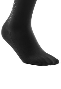 Zwarte sok gemaakt van een glad, rekbaar materiaal. Heeft een gestructureerde zool met een patroon van kleine witte stippen aan de zijkant.