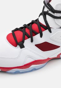 Zapatilla alta blanca con cordones negros, detalles rojos y malla. Presenta una mediasuela roja moteada y una suela exterior azul transparente.