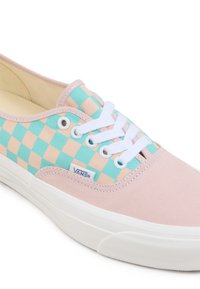Zapatillas de lona rosa claro con un patrón de cuadros azul y crema en la parte superior, cordones blancos y suela de goma. Presenta una etiqueta con el logotipo de Vans.