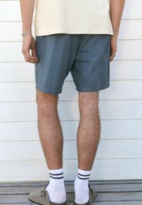 Szürke mintás, textúrált felületű, térd fölötti sort, amelyet fekete csíkos fehér zoknikkal és slip-on cipőkkel viselnek.