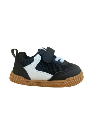 Zapatilla en blanco y negro con parte superior de malla, suela de goma, tira de Velcro y acentos texturizados. Nombre de la marca "Blanditos by Crío's" visible.