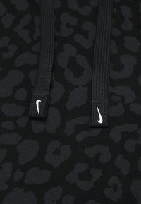 Black hoodie with a subtle leopard print pattern, featuring textured drawstrings and two small white Nike logos.
