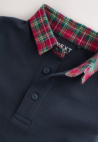 Navy blue polo shirt with three buttons and a folded red, green, and yellow plaid collar.