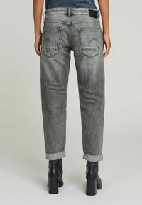 Grå denimbukser med en avslappet passform, med rullekanter, lommer med lapper og en mørk etikett på livet. Glatt, strukturert stoff.