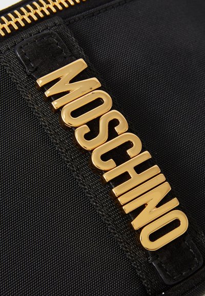 Juodas nailono maišelis su išsiskiriančiu auksiniu "MOSCHINO" logotipu. Tekstūruotas paviršius su lygiu užtrauktuku.