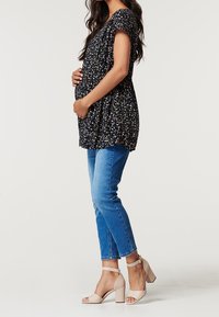 Flödande marinblå topp med liten blommönster, matchad med ljusblå kroppsnära jeans och beige klacksandaler. Mjuk tyg, avslappnad design.