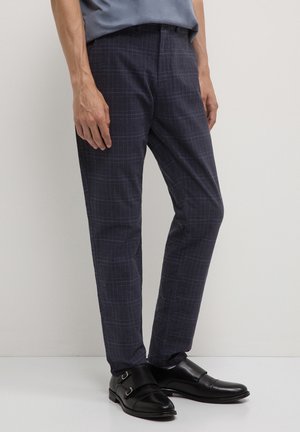 Marineblau karierte Hose mit slim fit, aus leichtem Stoff gefertigt. Merkmale ein dezent gemustertes Karomuster und ein taillierter Beinanschnitt. Kombiniert mit schwarzen Schuhen.