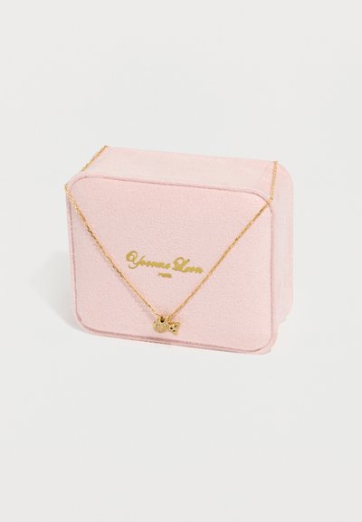 Λεπτό χρυσό κολιέ με δύο μικρά μενταγιόν σε σχήμα γάτας, τοποθετημένο σε απαλό ροζ κουτί κοσμημάτων με χρυσά γράμματα.