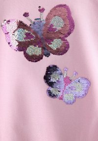 Ροζ ύφασμα με δύο σχέδια πεταλούδων από λαμπερά παγιέτες σε αποχρώσεις του μωβ, μπλε και ασημί, με λεπτομερή μοτίβα και διακοσμητικά στοιχεία.