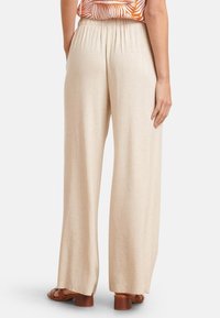 Beige, weite Hosen mit gerafftem Bund, aus einem leichten Stoff gefertigt. Das Design zeichnet sich durch eine glatte Textur und lockere Passform aus.
