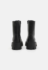 Black leather boots with a chunky sole, zipper closure at the back, and a smooth texture. Elevated, rugged design with minimal accents.