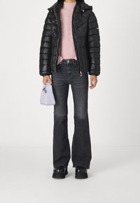 Giacca a vento nera con cappuccio, maglione rosa lavorato a maglia, jeans neri a zampa, e borsa lavanda. Scarpe con tacco nero completano l'outfit.