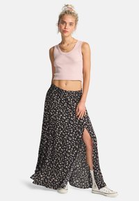 Lyserød cropped tanktop og sort blomster maxi-nederdel med en sideslids. Nederdelen har små hvide og lavendelblomster på en sort baggrund.