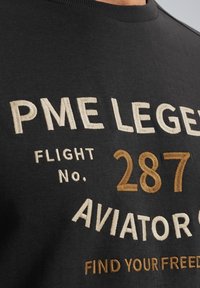 Crni pamučni dukserica s izvezenim tekstom. Karakteristike uključuju "PME Legend", "AVIATOR" i detalje o letu u svijetlosmešavoj i zlatnoj niti.