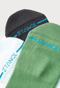 Tre par sokker i sort, grøn og lyseblå med ribbet tekstur. Hver sok understreger "STANCE"-logoet i kontrasterende blå.