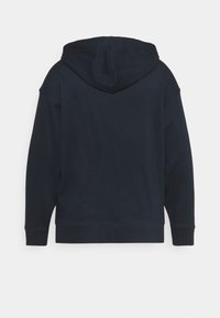 Sweat à capuche bleu marine avec tissu texturé, poignets et ourlet côtelés. Présente une couture arrière et une poche kangourou à l'avant.