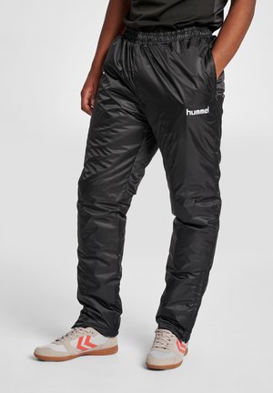 Schwarze, glänzende, leichte Trainingshosen mit einem elastischen Bund und Taschen. Mit weißem Logo und Seitennähten mit subtiler Textur.