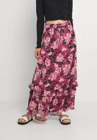 Falda maxi floral en rosa intenso y negro, con volantes y cintura con cordón, hecha de una tela ligera y fluida.