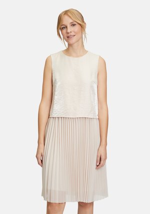 Helles beige Kleid mit einem glänzenden, ärmellosen Oberteil und einem plissierten Rock. Strukturierter Stoff mit einer glatten Oberfläche am Oberteil und einem fließenden unteren Teil.