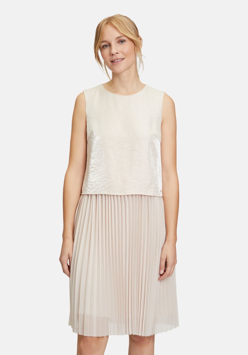 Helles beige Kleid mit einem glänzenden, ärmellosen Oberteil und einem plissierten Rock. Strukturierter Stoff mit einer glatten Oberfläche am Oberteil und einem fließenden unteren Teil.