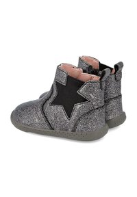 Botas de tobillo negras brillantes con un destacado diseño de estrella, paneles laterales elásticos y suelas grises. Textura suave con un forro interior rosa claro.