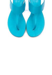 Türkise Sandalen mit flacher Sohle, die ein zentrales Zehenband und einen breiten Riemen oben haben. Glattes, glänzendes Plastikmaterial.