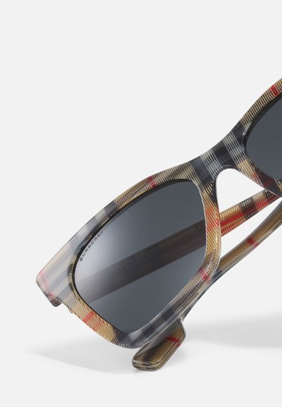 Transparente Sonnenbrille mit einem karierten Muster in Grau, Rot und Beige; rechteckige Gläser und einzigartiges Auschnitt-Design an der Seite.
