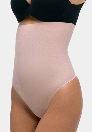 Woman wearing high-waisted, light pink shapewear briefs with a subtle leopard pattern and a black bra against a plain background.