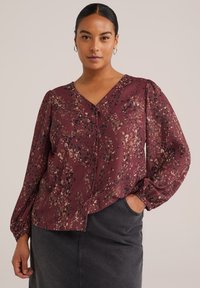 Blusa bordeaux a fantasia con scollo a V, caratterizzata da una combinazione di macchie metalliche dorate, nere e marroni, e maniche lunghe a sbuffo. Chiusura con bottoni frontale.
