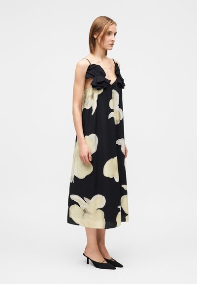 Μαύρο φόρεμα με μεγάλα κρεμ χρώματος λουλούδια και τιράντες με βολάν. Απαλό ύφασμα �με χαλαρή, αέρινη σιλουέτα.