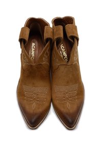 Stivali alla caviglia in suede marrone con punta appuntita, dettagli cuciti e cinghie intorno alle caviglie per una sicura chiusura.