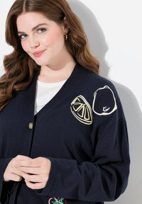 Mörkblå cardigan med långa ärmar, med broderade citrondagar och citronskivor på axlarna och en rund knappstängning.