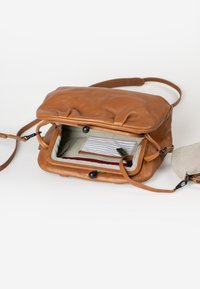 Bruine leren schoudertas met een bovenklep, gestreepte binnenvoering en een klein vastgemaakt tasje. Voorzien van ritssluitingen en een verstelbare schouderband.