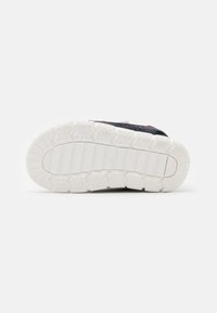 Dziecięce sneakersy z teksturowaną białą gumową podeszwą oraz czerwono-czarnym wierzchem, zaprojektowane z myślą o przyczepności i trwałości.